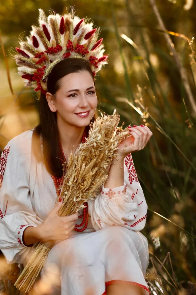 Retrato de mujer con corona de espigas y camisa bordada en el campo