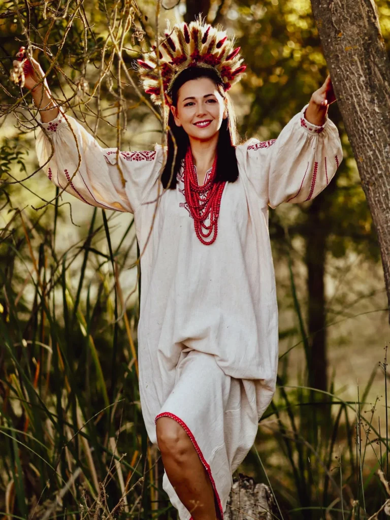 Mujer con camisa bordada tradicional y corona de flores entre encinas